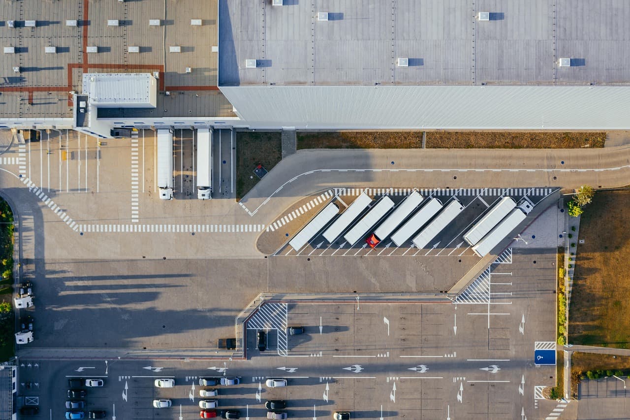 Camions et entrepôt logistique illustrant une chaîne d'approvisionnement et de sous-traitance industrielle