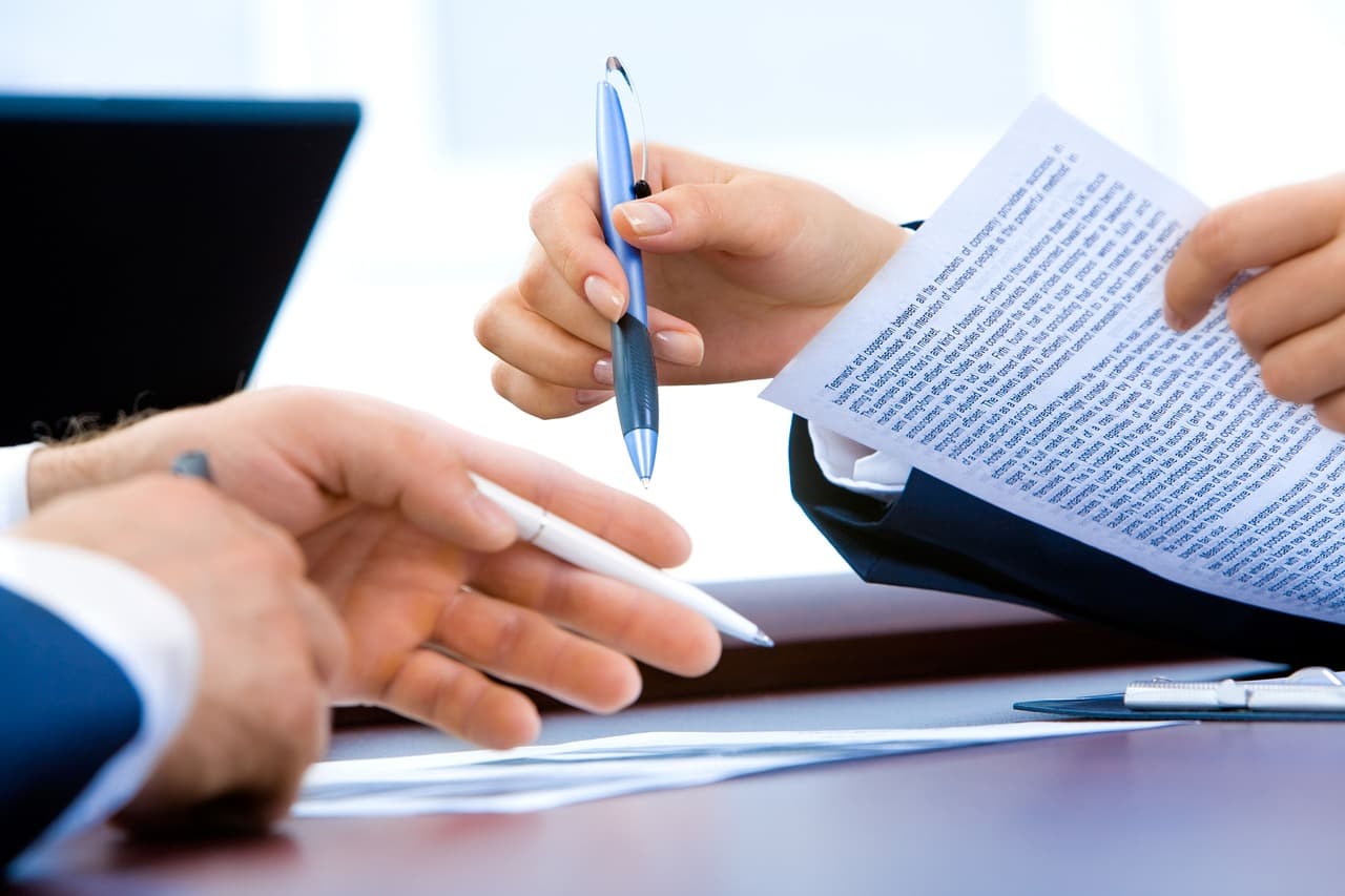 Documents contractuels et classeurs organisés sur une étagère de bureau