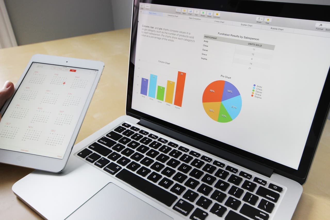 Équipe de travail réunie autour d'une table avec ordinateurs portables et tablette, échange professionnel