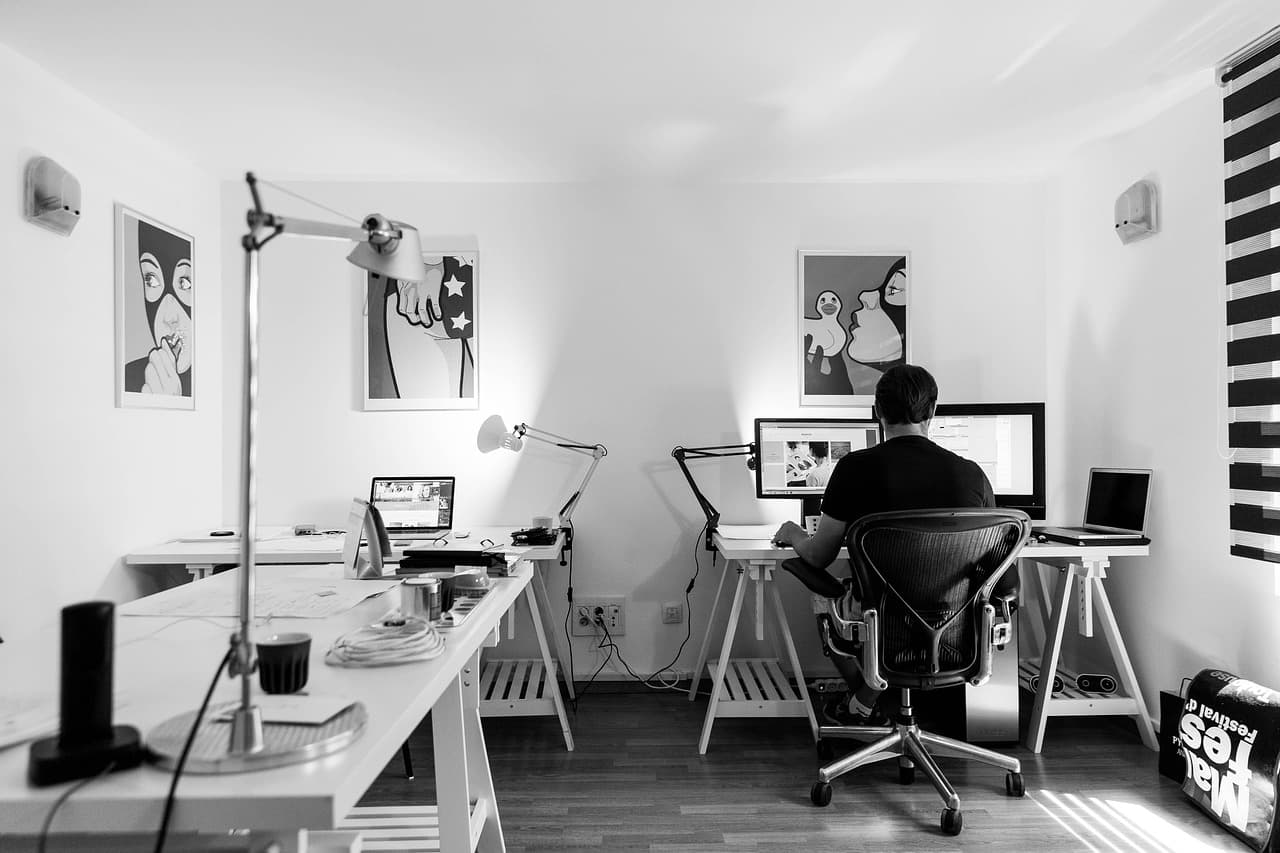 Développeur de dos travaillant sur plusieurs écrans dans un bureau à domicile
