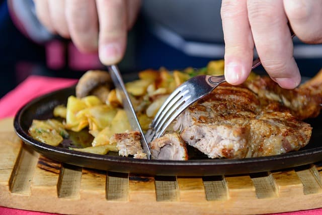Table dressée dans une salle de restaurant, avec couverts et verres disposés